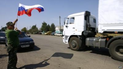 Man holds Russian flag as lorry crosses border