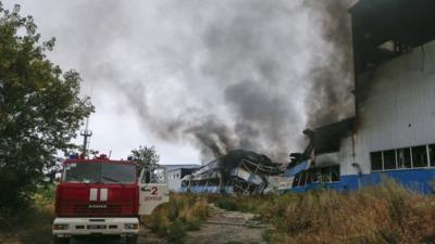 A fire engine is parked next to burning printing factory hit by what locals say, was recent shelling by Ukrainian forces in Donetsk August 23, 2014