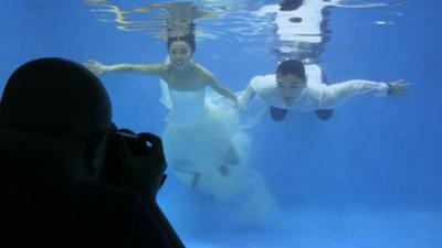 A bride and groom go underwater for their wedding snaps