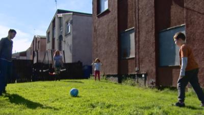 Family surrounded by derelict housing