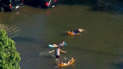 People on lilos in flooded street