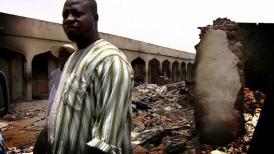 A man standing in front of damaged buildings