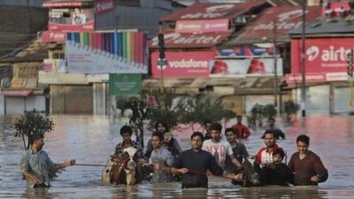 In Kashmir, residents have waded through neck-deep waters with their belongings.