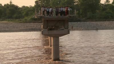 Spectators at snapped end of bridge