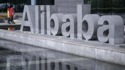 People walking past Alibaba sign