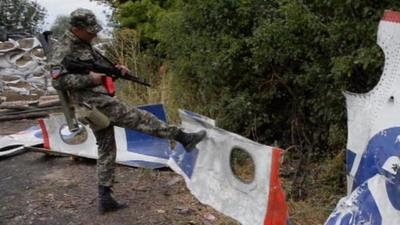 A pro-Russian separatist kicks a piece of wreckage at the MH17 crash site