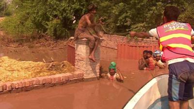 Rescue worker on boat throws rope to family in deep water