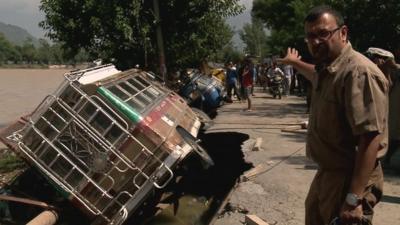 Sanjoy Majumder pointing at overturned vehicles in Srinagar