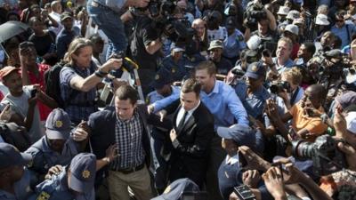 South African Paralympic athlete Oscar Pistorius (C) is surrounded by members of the media as he leaves the High Court after the verdict hearing of his trial over the killing of his model girlfriend Reeva Steenkamp, on September 11, 2014 in Pretoria