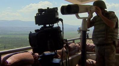 Turkish soldier surveying border through telescope