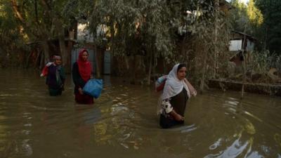 Kashmiri residents wade through floodwaters in Rakshalana south of Srinagar