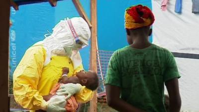 A health worker holds a baby in an Ebola hit region