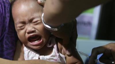 A child cries as a local health worker administers a vaccine