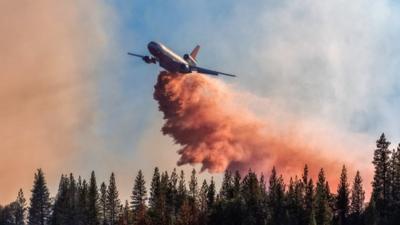DC-10 drops fire retardant over a wildfire in California
