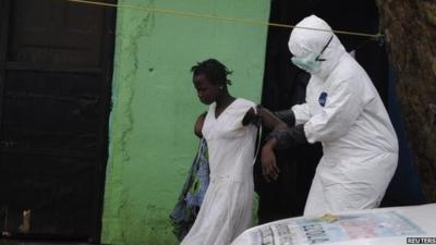 A woman and an Ebola health worker in a protective suit