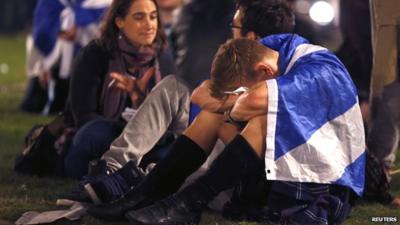 A man draped in a Scottish flag, hunched over in despair