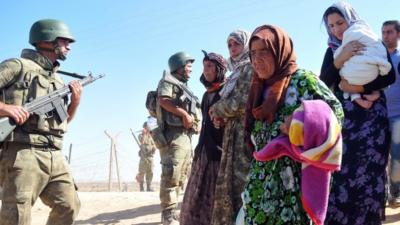 Syrian Kurds walk after crossing into Turkey at the Turkish-Syrian border