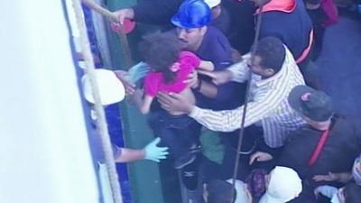 Girl being passed from fishing boat to the cruise ship