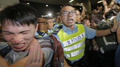 A protester, left, reacts after police officers used pepper spray against protesters attempting to break into government building