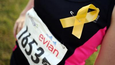 Runner in the Ealing half-marathon in London wearing a yellow ribbons in support of the campaign to find missing teenager Alice Gross