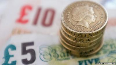 Close up of pound coins resting on a £5 and £10 note