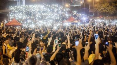 Pro-democracy protesters hold up their mobile phones as lights in front of the Hong Kong government offices on day three of the mass civil disobedience campaign Occupy Central in Hong Kong