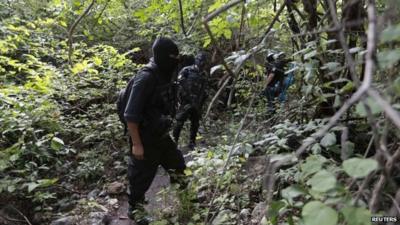 Police officers stand guard in an area where a mass grave was found