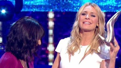 Claudia Winkleman (left) looks on as Tess Daly (right) holds up her silver shoe