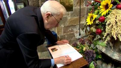 People sign a book of condolence at Eccles Parish Church