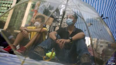 Protesters sitting behind umbrella