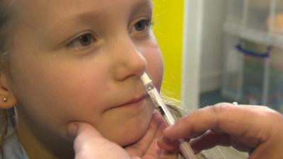 Child receiving vaccine in nostril