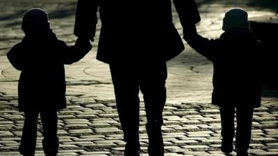 A women with two children walking on a street