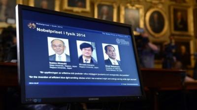 The portraits of researchers (L-R) Isamu Akasaki, Hiroshi Amano and Shuji Nakamura are displayed on a screen