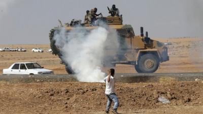 A protester throws stones at an armoured army vehicle during a pro-Kurdish demonstration
