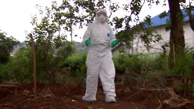 The BBC's Tulip Mazumdar in full biohazard kit reporting from Sierra Leone