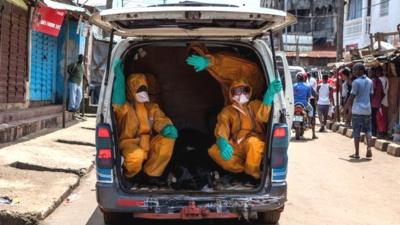 Volunteers arrive to pick up bodies of people who have died of the Ebola virus