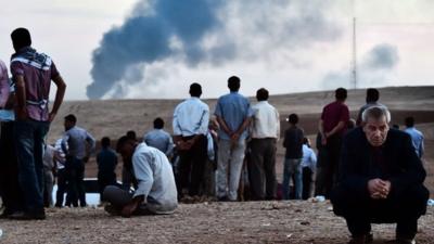 Man look on as smoke rises over Kobane