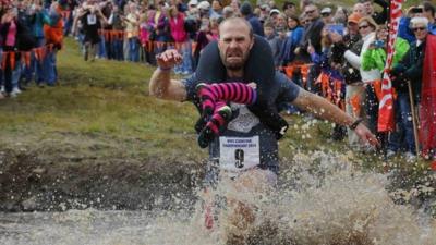 Eventual winners Jesse Wall carries Christina Arsenault through the water pit while competing in the North American Wife Carrying Championship at Sunday River ski resort in Newry, Maine October 11, 2014