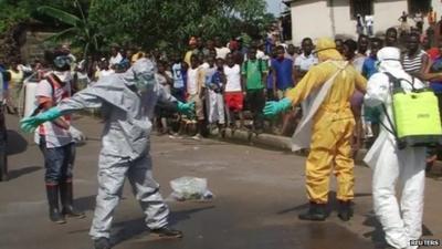 Sierra Leone burial team disinfecting themselves after removing body from street