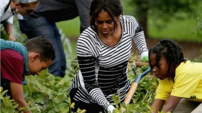 Michelle Obama and children harvesting vegetables