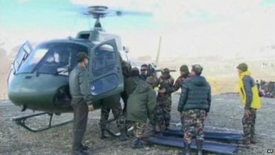 Rescuers in Nepal about to remove someone from a rescue helicopter and put them on a stretcher