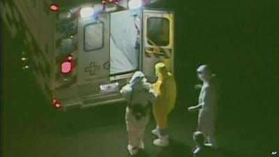 Ebola patient Amber Vinson (in yellow) is helped towards ambulance after arriving in Atlanta for treatment