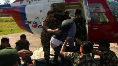 A rescued man is helped from a helicopter