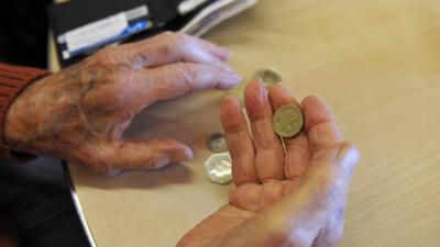 A pensioner holding coins