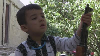 Afghan boy playing with gun