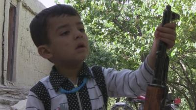 Afghan boy playing with gun