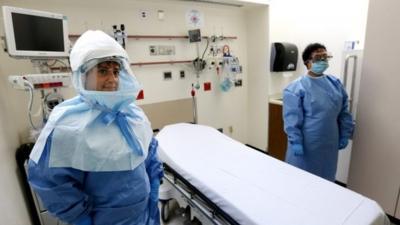 Two medical workers wear protective suits inside an isolation room appropriate to handle people inflected with the Ebola virus at Bellevue Hospital Center in New York, New York