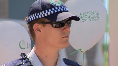 Australian policeman standing in front of balloon with 'National Mosque Open Day' logo