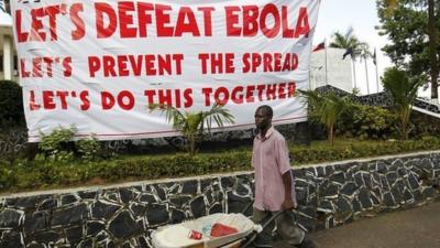 Man walking past Ebola sign