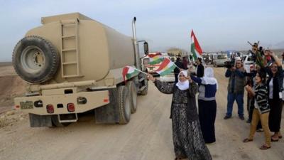 A convoy of peshmerga vehicles is welcomed by Turkish Kurds after crossing into Turkey